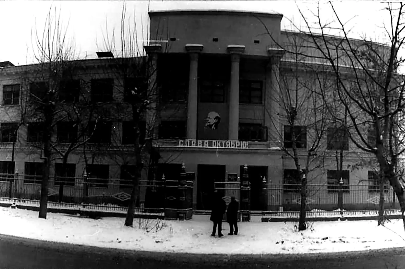 Исторический вид школьного сада с декоративной каменной вазой на переднем плане.